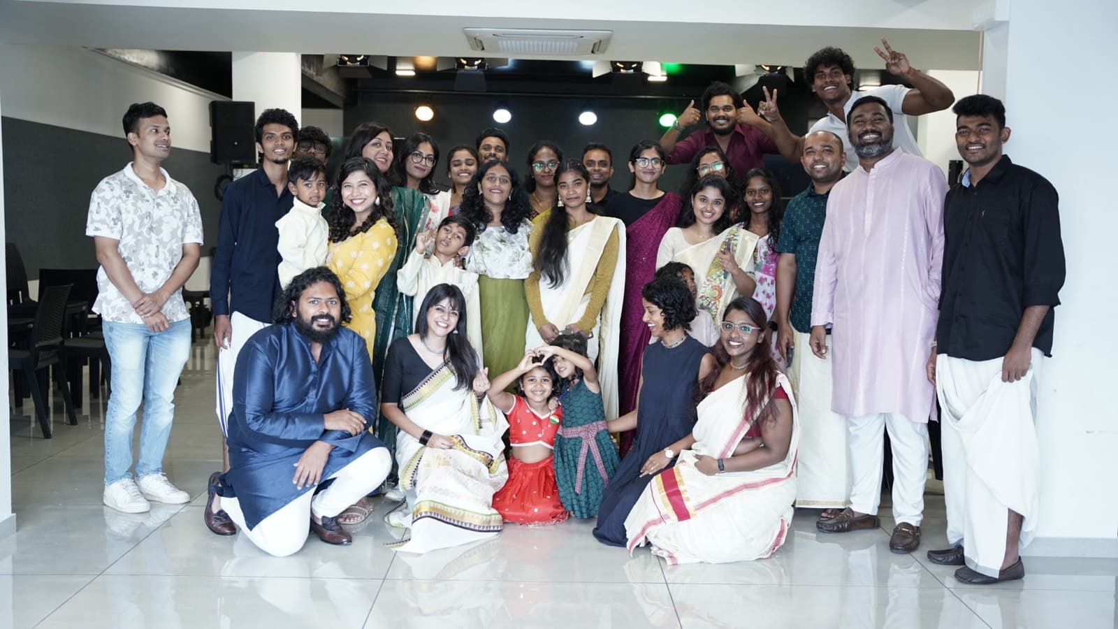 The ECC youth, dressed in traditional Kerala clothes, smiling for a group photo